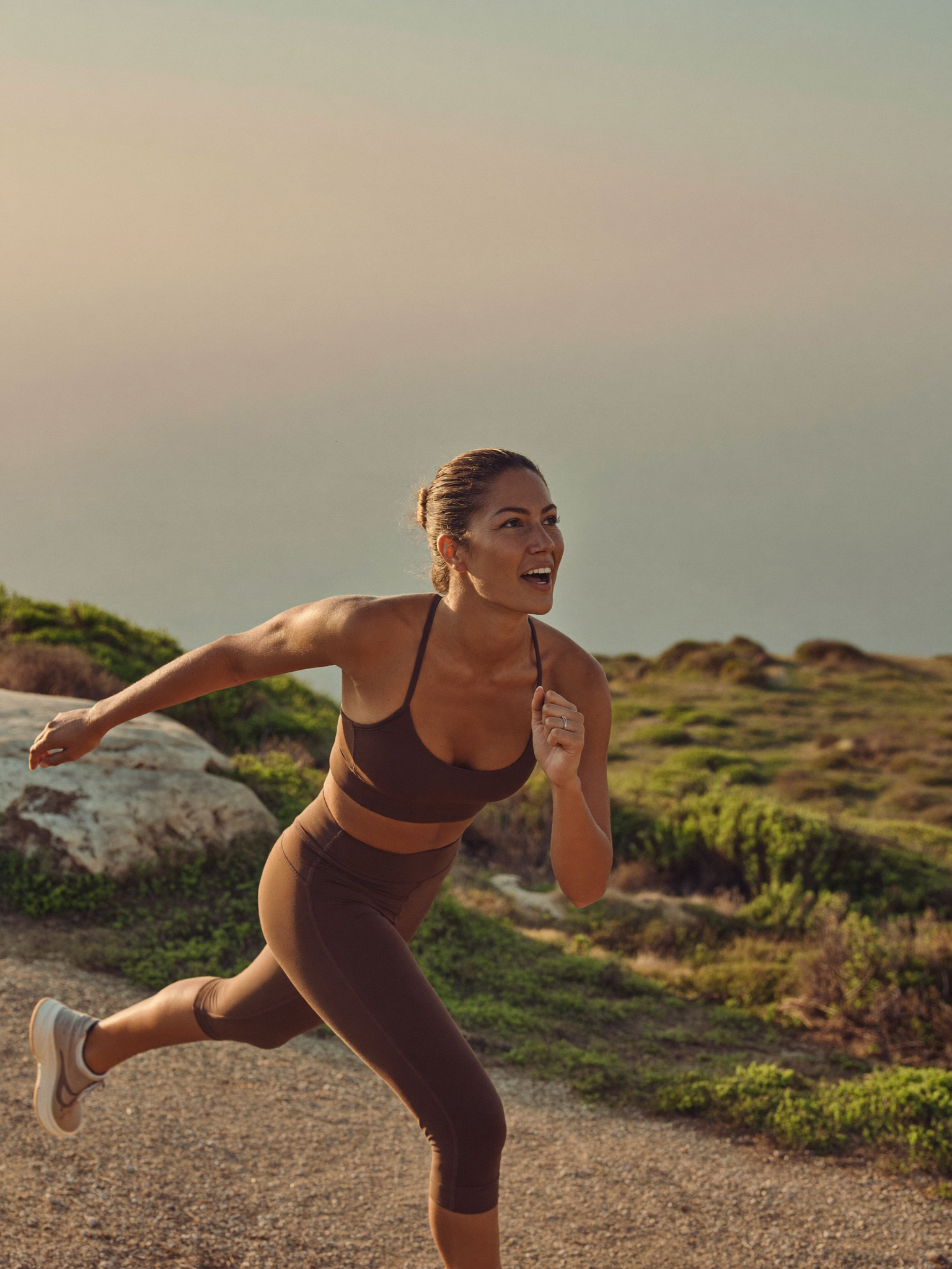 Energy & Performance — a woman finishing a sunrise run, energized and strong